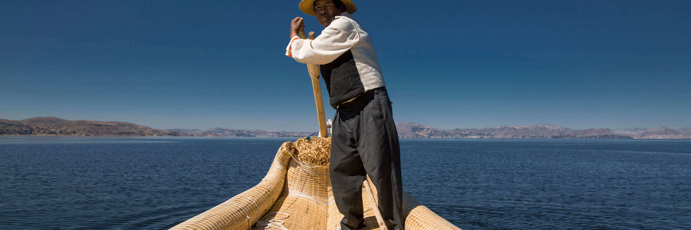 Traditional reed boat glides across Peru's Lake Titicaca in the Andean highlands. 