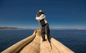 Traditional reed boat glides across Peru's Lake Titicaca in the Andean highlands.