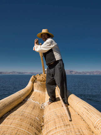 Traditional reed boat glides across Peru's Lake Titicaca in the Andean highlands.