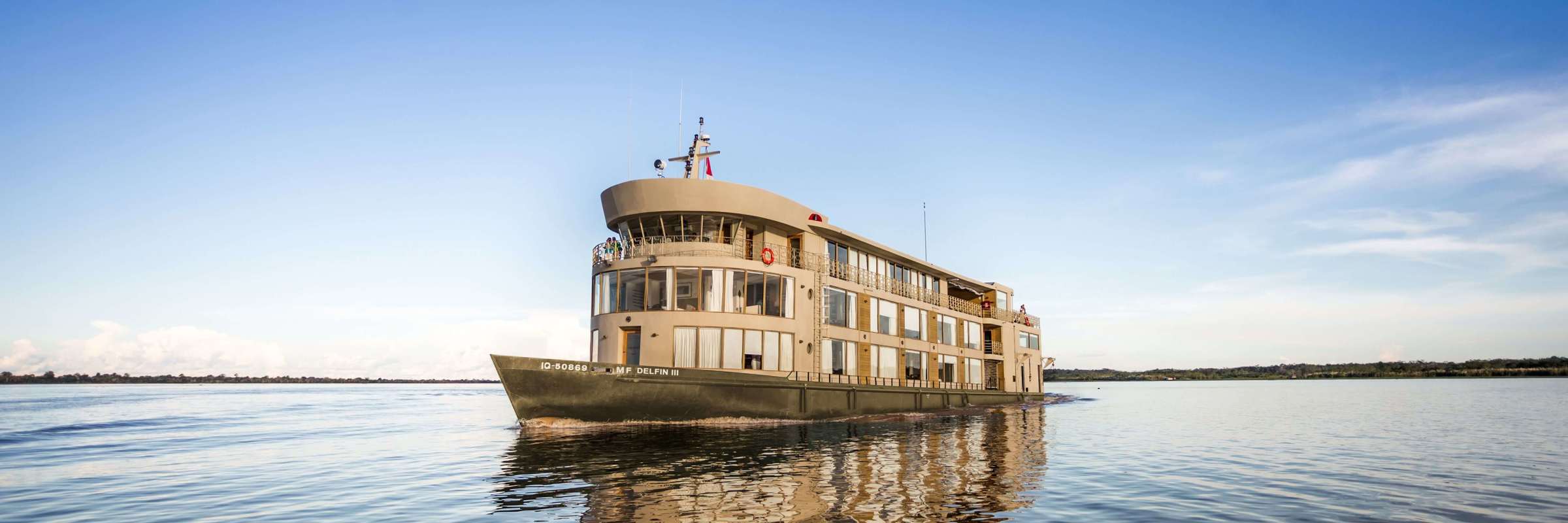 The Delfin III glides over glassy Amazon waters, offering luxury and adventure deep in the jungle. 