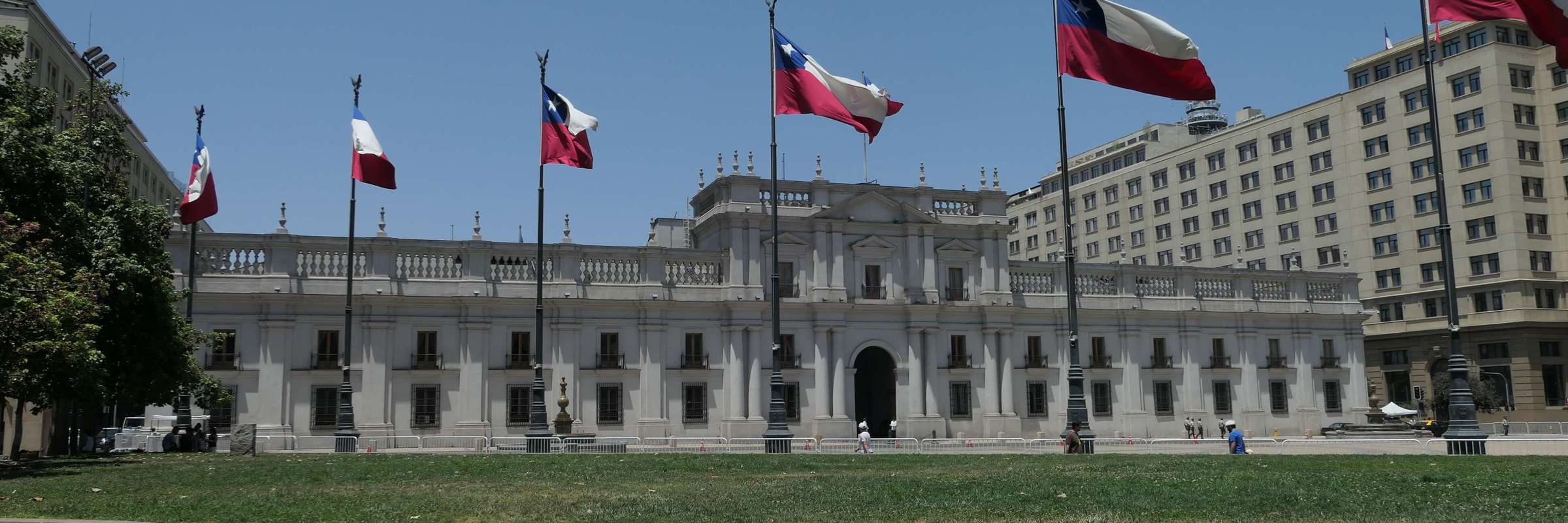 La Moneda Palace in Santiago, Chile framed by waving national flags on a clear day in the capital's civic center. 