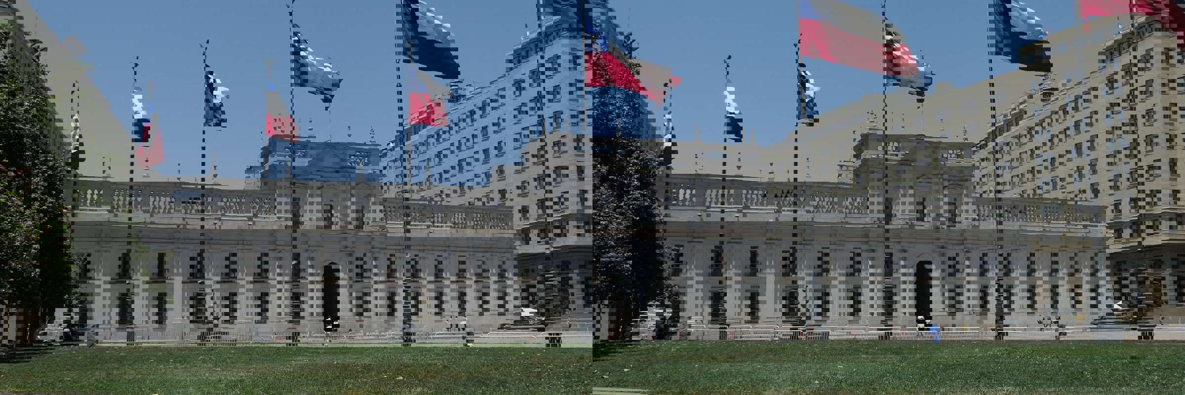 La Moneda Palace in Santiago, Chile framed by waving national flags on a clear day in the capital's civic center. 