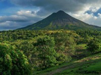 Central America - Costa Rica, lush greenery surrounding the majestic Arenal Volcano under a bright blue sky. 