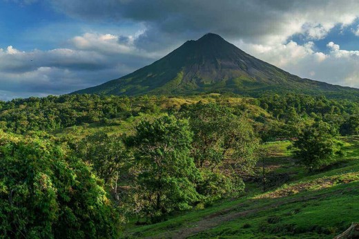 Central America - Costa Rica, lush greenery surrounding the majestic Arenal Volcano under a bright blue sky. 