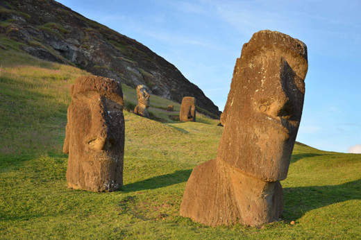 Ancient Moai statues partially buried on the grassy slopes of Rano Raraku, the volcanic quarry on Easter Island where these iconic figures were carved centuries ago. 