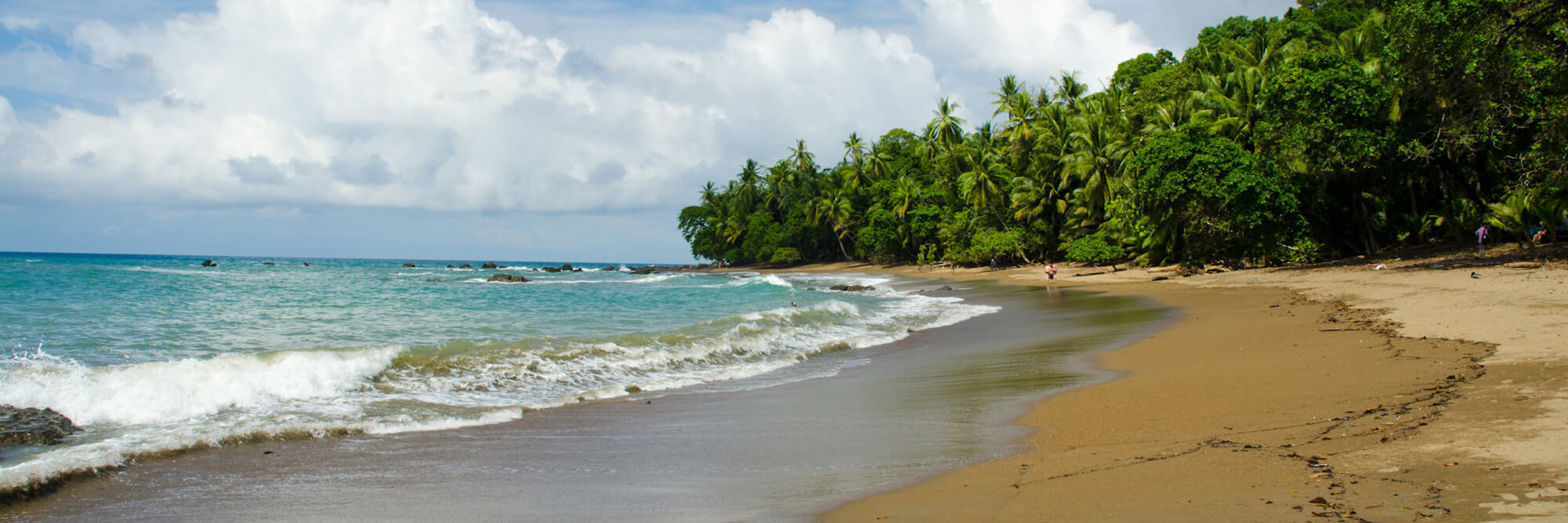 Golden sand beach with turquoise waves and lush rainforest on the coast of Costa Rica. 