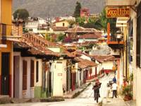 Cobbled street in San Cristobal de las Casas, Mexico, with colonial buildings, colourful facades, and locals walking. 