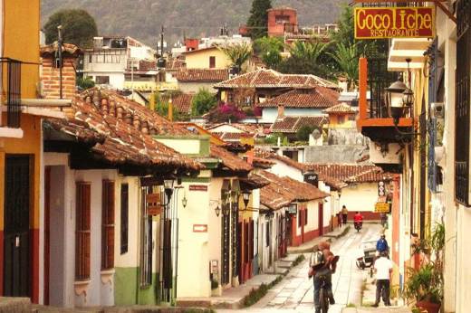Cobbled street in San Cristobal de las Casas, Mexico, with colonial buildings, colourful facades, and locals walking. 