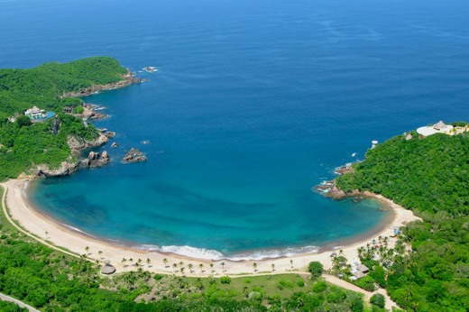 Aerial view of Costa Careyes, showcasing a secluded crescent-shaped beach and lush greenery along Mexico's Pacific Coast. 