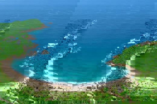 Aerial view of Costa Careyes, showcasing a secluded crescent-shaped beach and lush greenery along Mexico's Pacific Coast. 