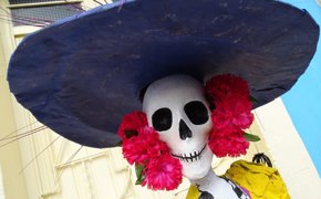 Colourful Day of the Dead Catrina figure with wide hat and flowers, part of Mexico's Dia de los Muertos celebrations. 
