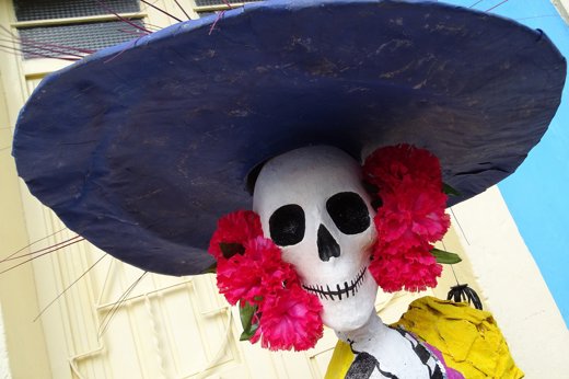 Colourful Day of the Dead Catrina figure with wide hat and flowers, part of Mexico's Dia de los Muertos celebrations. 