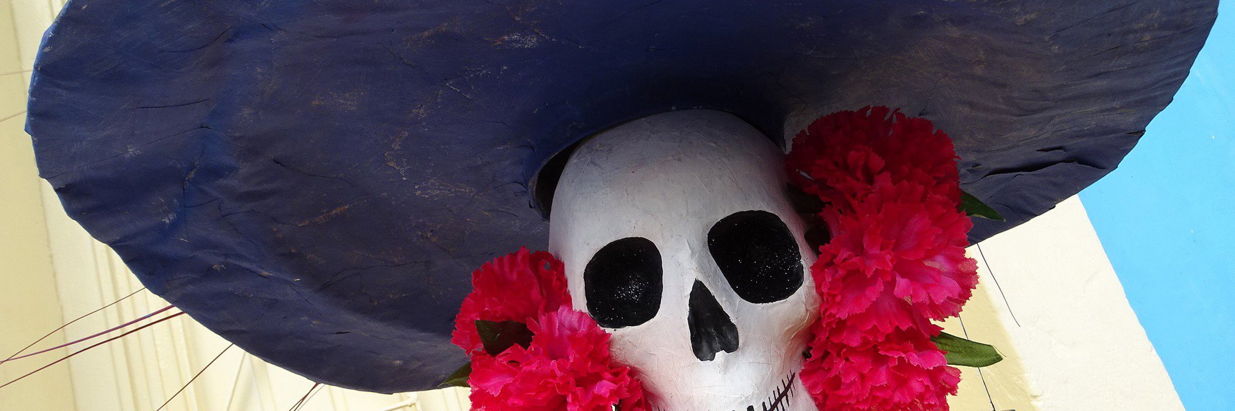 Colourful Day of the Dead Catrina figure with wide hat and flowers, part of Mexico's Dia de los Muertos celebrations. 
