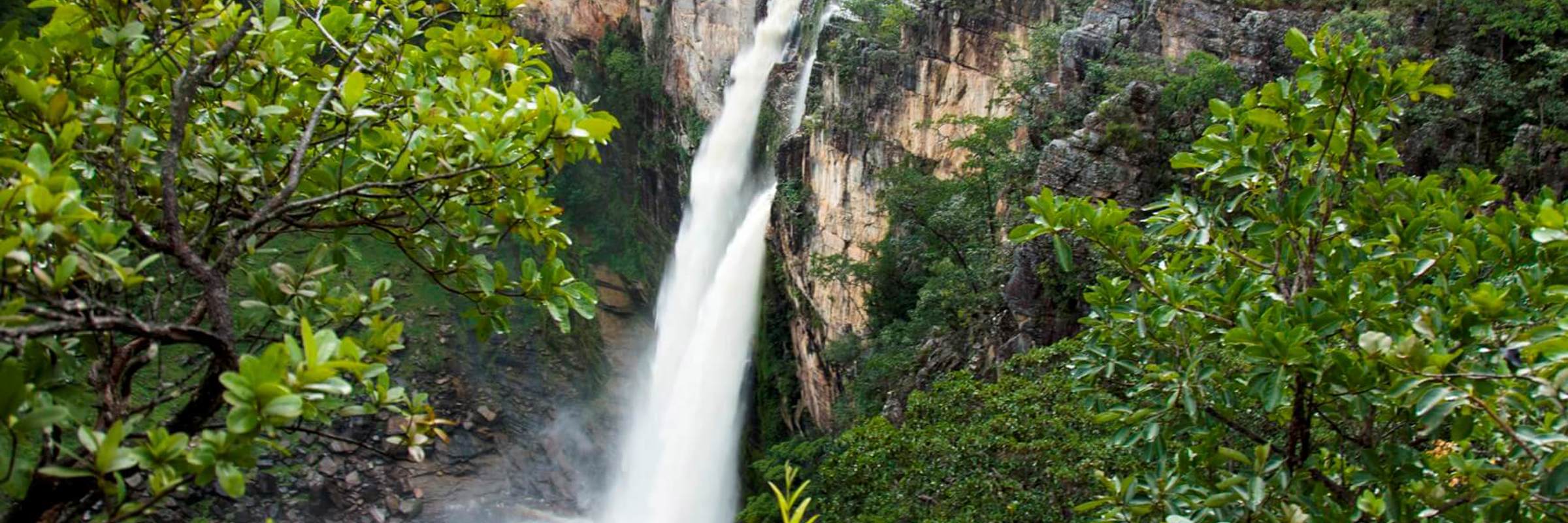 Tall waterfall surrounded by lush green forest in Chapada dos Veadeiros National Park, central Brazil. 