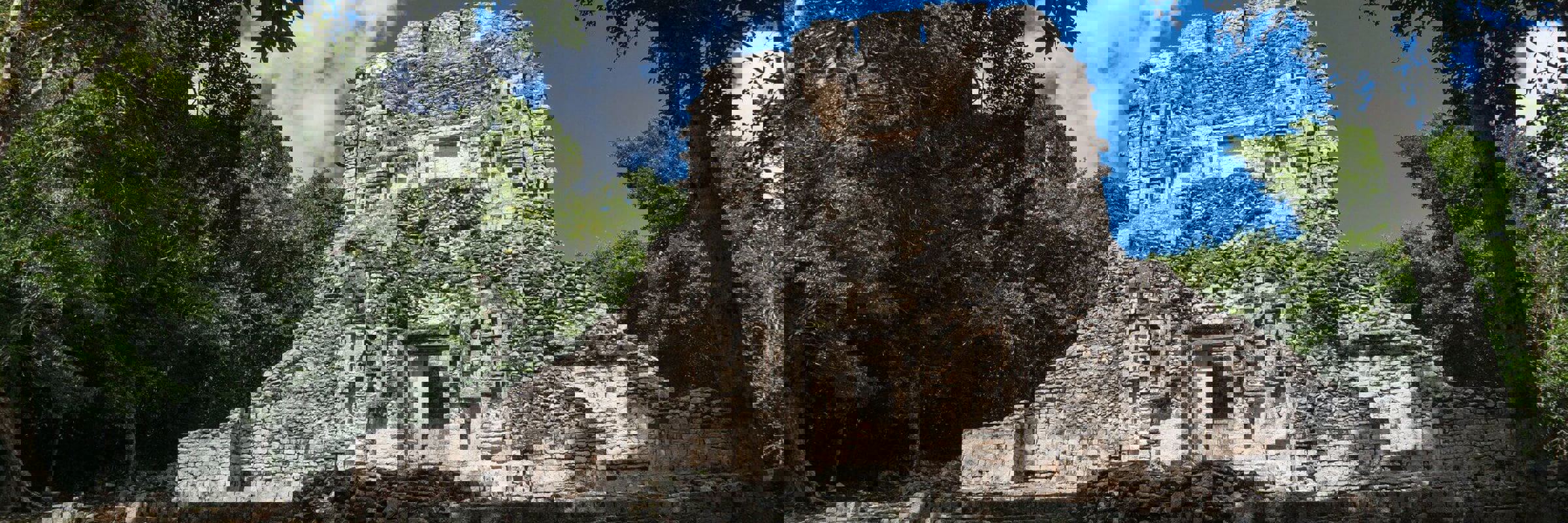 The main temple at Chicanna archaeological site, surrounded by jungle, featuring intricate Maya stucco decorations. 