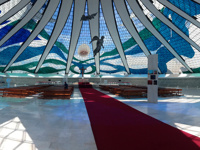 Interior of the Cathedral of Brasilia, showcasing stained glass ceiling and suspended angel sculptures in modernist design. 