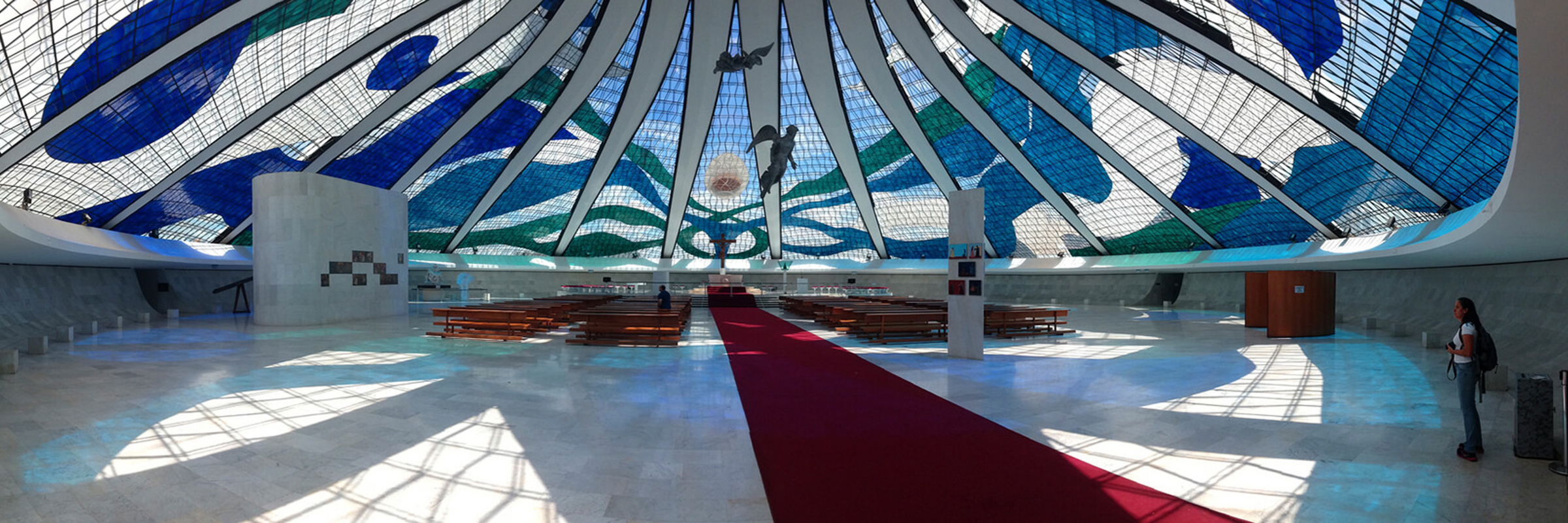 Interior of the Cathedral of Brasilia, showcasing stained glass ceiling and suspended angel sculptures in modernist design. 