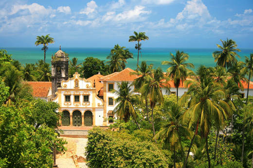 View of colonial architecture, church towers, and palm trees in Olinda overlooking the Atlantic coast near Recife, Brazil. 