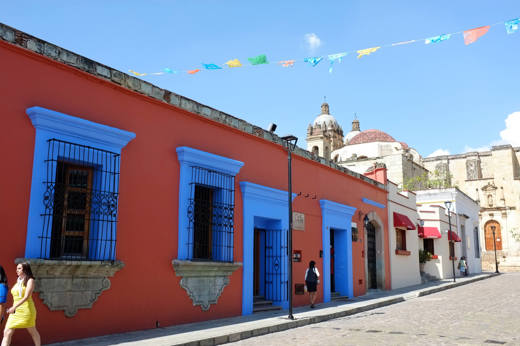 Colourful colonial buildings with bright blue windows and festive papel picado banners in the streets of Oaxaca, Mexico. 