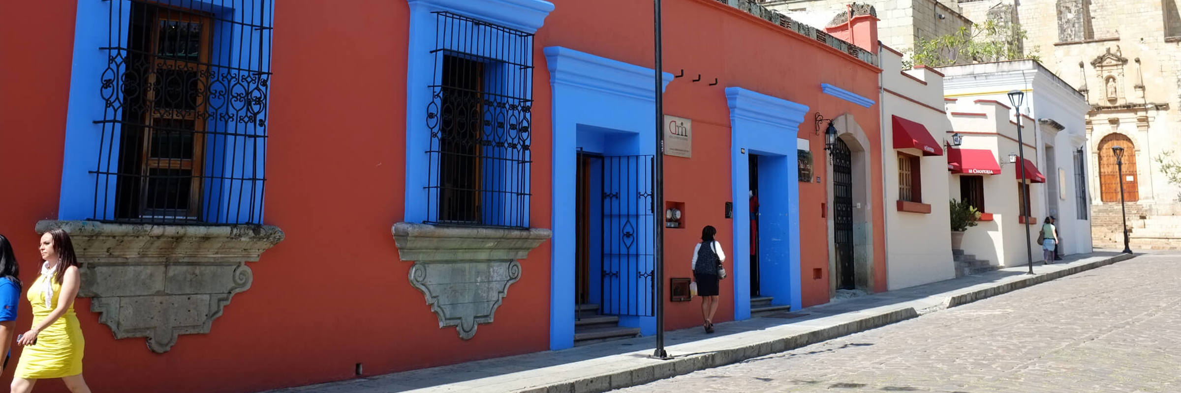Colourful colonial buildings with bright blue windows and festive papel picado banners in the streets of Oaxaca, Mexico. 