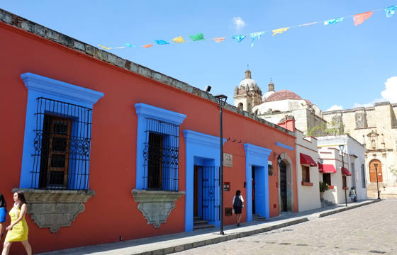 Colourful colonial buildings with bright blue windows and festive papel picado banners in the streets of Oaxaca, Mexico.