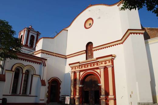 Colonial-style church with white facade and red trim under a clear blue sky in Tehuantepec, Mexico. 