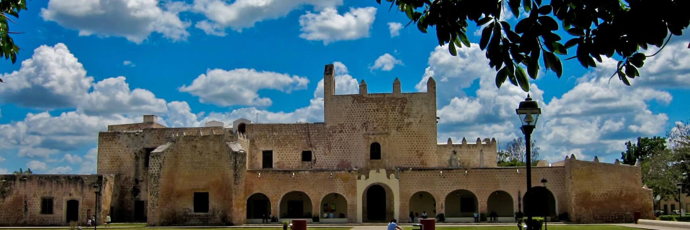 Colonial-era Convento de San Bernardino in Valladolid, Yucatan, framed by a bright sky and well-kept gardens. 