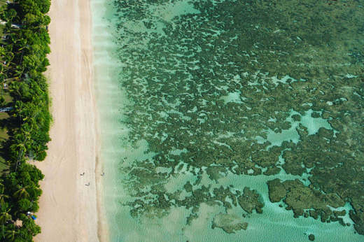 Aerial view of the turquoise sea, coral reef, and tropical shoreline at Morro de Sao Paulo, Bahia, Brazil. 