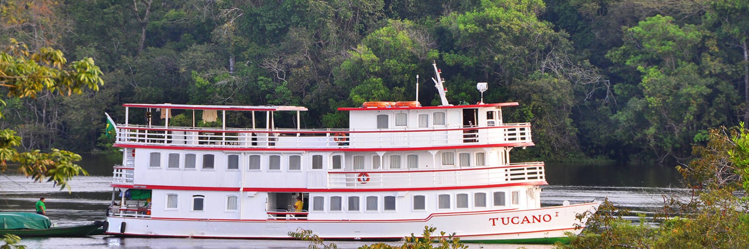 The Tucano Amazon cruise boat on the Rio Negro surrounded by lush rainforest, near Manaus, Brazil. 