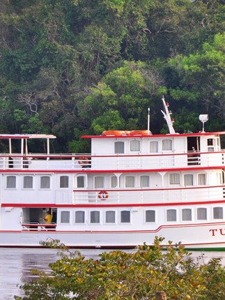 The Tucano Amazon cruise boat on the Rio Negro surrounded by lush rainforest, near Manaus, Brazil.