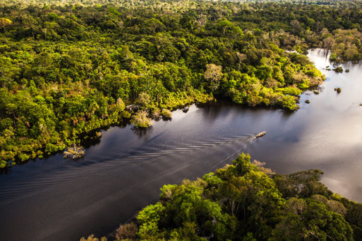 South America - Brazil, Aerial view of a boat cruising through the Amazon surrounded by lush rainforest.  