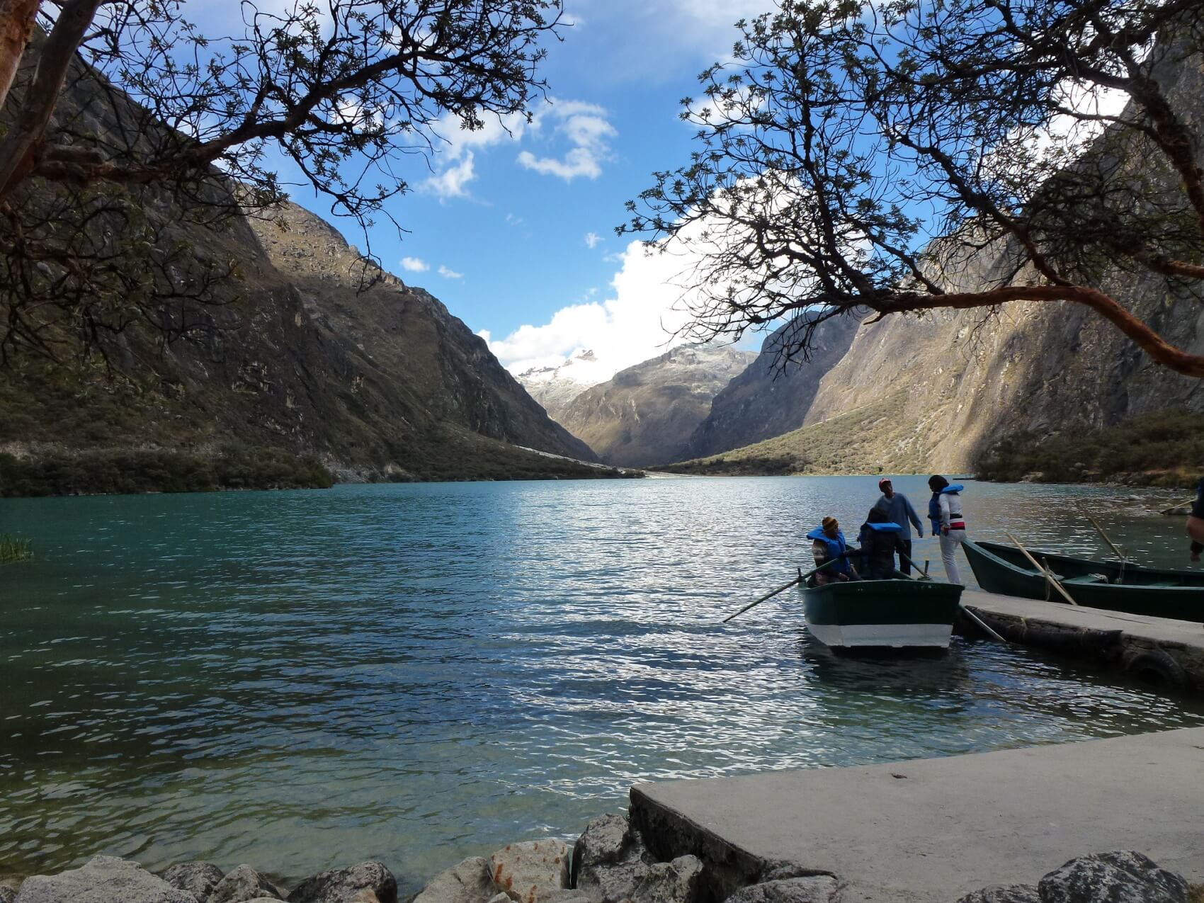 Scenic lake in Huaraz with mountains and boat under a clear sky in the Peruvian Andes. 
