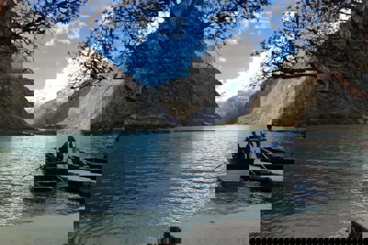 Scenic lake in Huaraz with mountains and boat under a clear sky in the Peruvian Andes. 