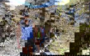 A family hikes together along a rugged mountain trail, immersed in Peru's Sacred Valley landscape.