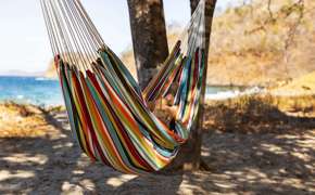 Relaxing in a colourful hammock strung between palm trees on a quiet tropical beach. 
