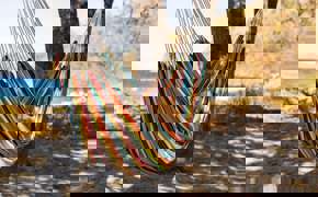 Relaxing in a colourful hammock strung between palm trees on a quiet tropical beach.