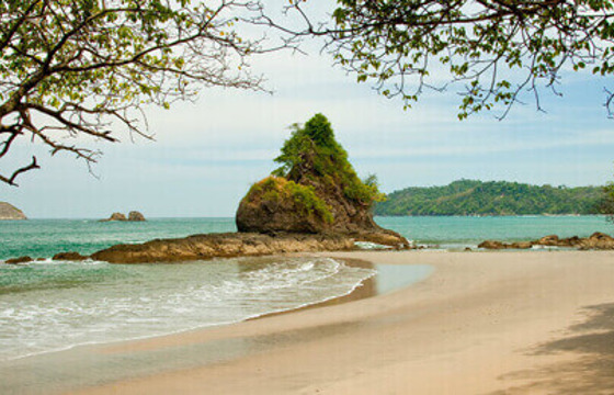 Golden sands and calm waves create a peaceful escape at Manuel Antonio's hidden beach cove. 