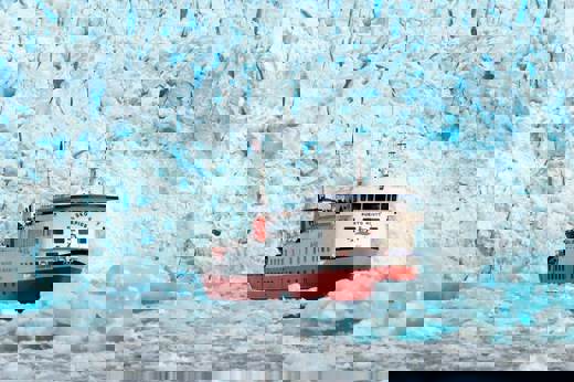 The Skorpios II cruise ship approaches the towering blue ice wall of a glacier in Chilean Patagonia. 