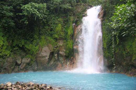 Vivid turquoise waters cascade into Rio Celeste's jungle pool in Tenorio Volcano National Park. 