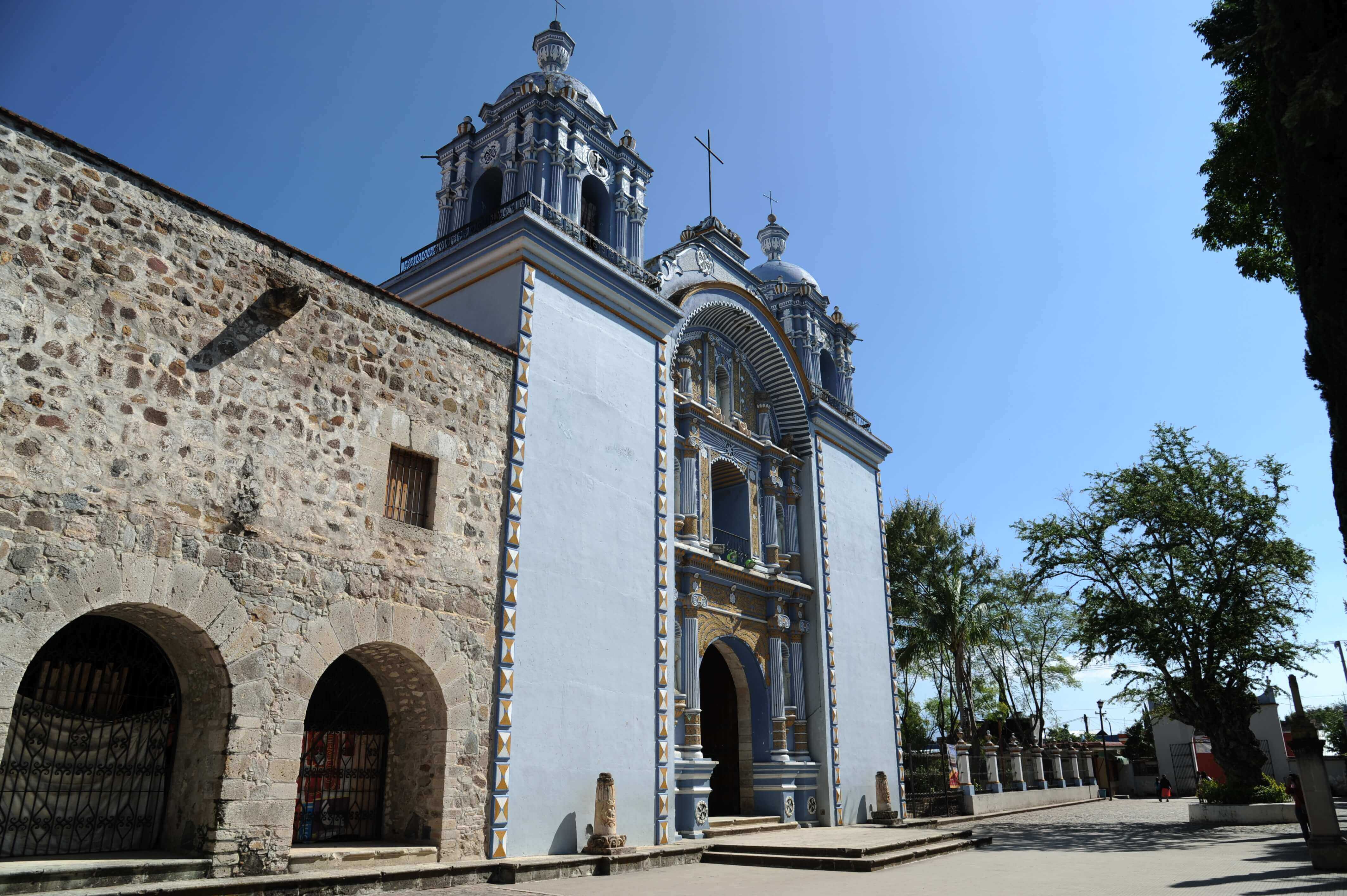 Elegant colonial church in Mexico with stone facade and baroque towers, standing beneath a clear blue sky. 