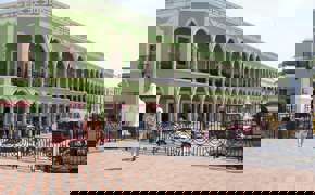 Historic green arcade building on Merida's Plaza Grande, Yucatan, with colonial arches, statue, and pedestrian view. 
