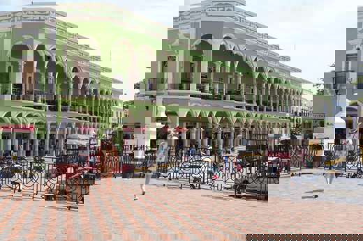 Historic green arcade building on Merida's Plaza Grande, Yucatan, with colonial arches, statue, and pedestrian view. 