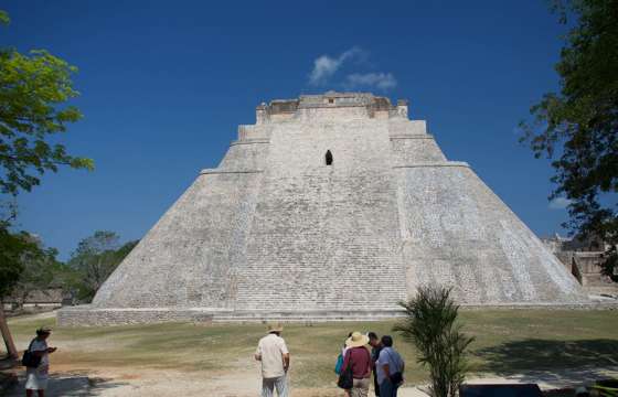 The Pyramid of the Magician at Uxmal, Yucatan, Mexico, a towering Mayan structure with steep sides and tourists at the base. 