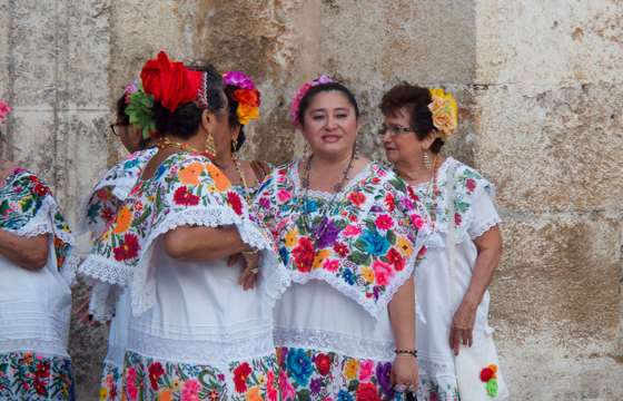 Women in traditional embroidered huipiles gather in Merida, Yucatan, showcasing vibrant local dress and culture. 