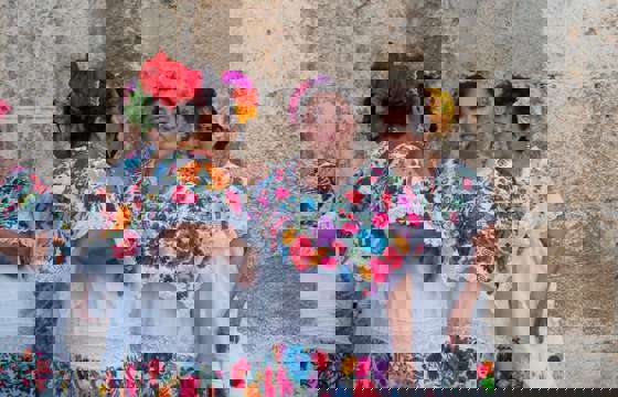 Women in traditional embroidered huipiles gather in Merida, Yucatan, showcasing vibrant local dress and culture.