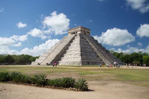 The Temple of Kukulcan at Chichen Itza rises under a bright sky, showcasing ancient Mayan architectural brilliance. 
