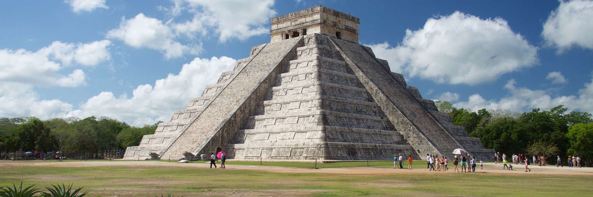 The Temple of Kukulcan at Chichen Itza rises under a bright sky, showcasing ancient Mayan architectural brilliance. 