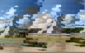 The Temple of Kukulcan at Chichen Itza rises under a bright sky, showcasing ancient Mayan architectural brilliance. 
