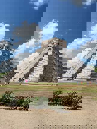 The Temple of Kukulcan at Chichen Itza rises under a bright sky, showcasing ancient Mayan architectural brilliance. 