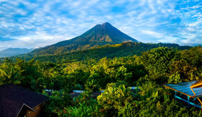 Arenal Volcano rises above the tropical forest of Costa Rica, framed by colorful lodges. 